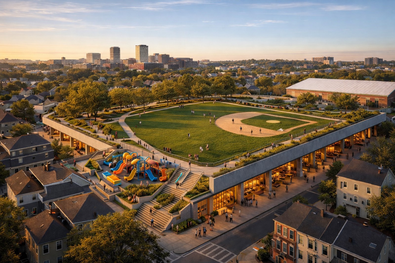 Aerial sunset rendering of Gold Star Mothers Park as a deck park — a baseball field on a structural lid, with a children's playground and neighborhood restaurants beneath, Cambridge triple-deckers in the foreground and the Boston skyline on the horizon.